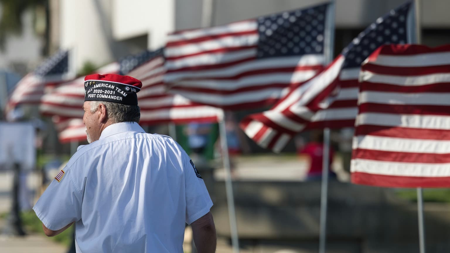 A veteran marches in a parade with U.S. flags in the background