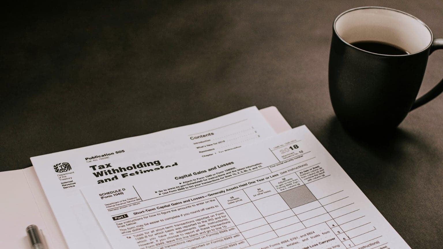 Tax forms next to a coffee cup on a table