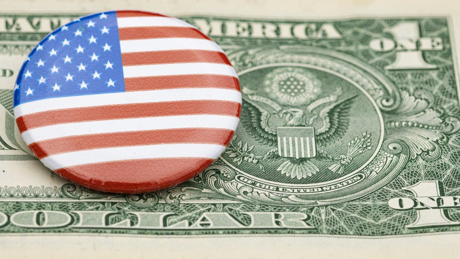 A U.S. flag button on top of a dollar bill