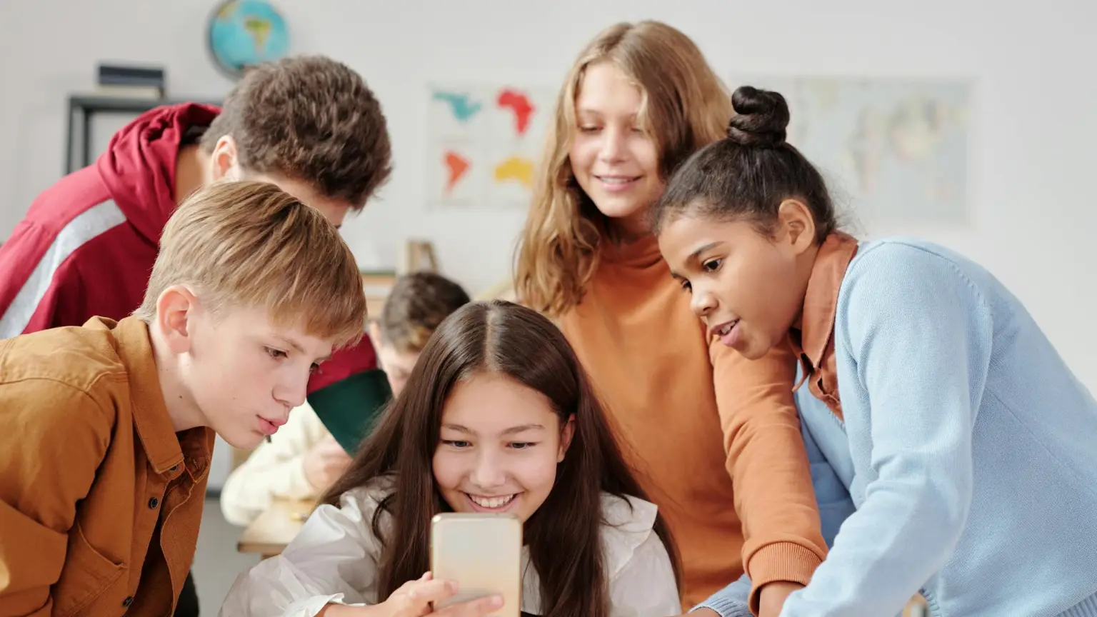 Five school kids all looking at a smartphone