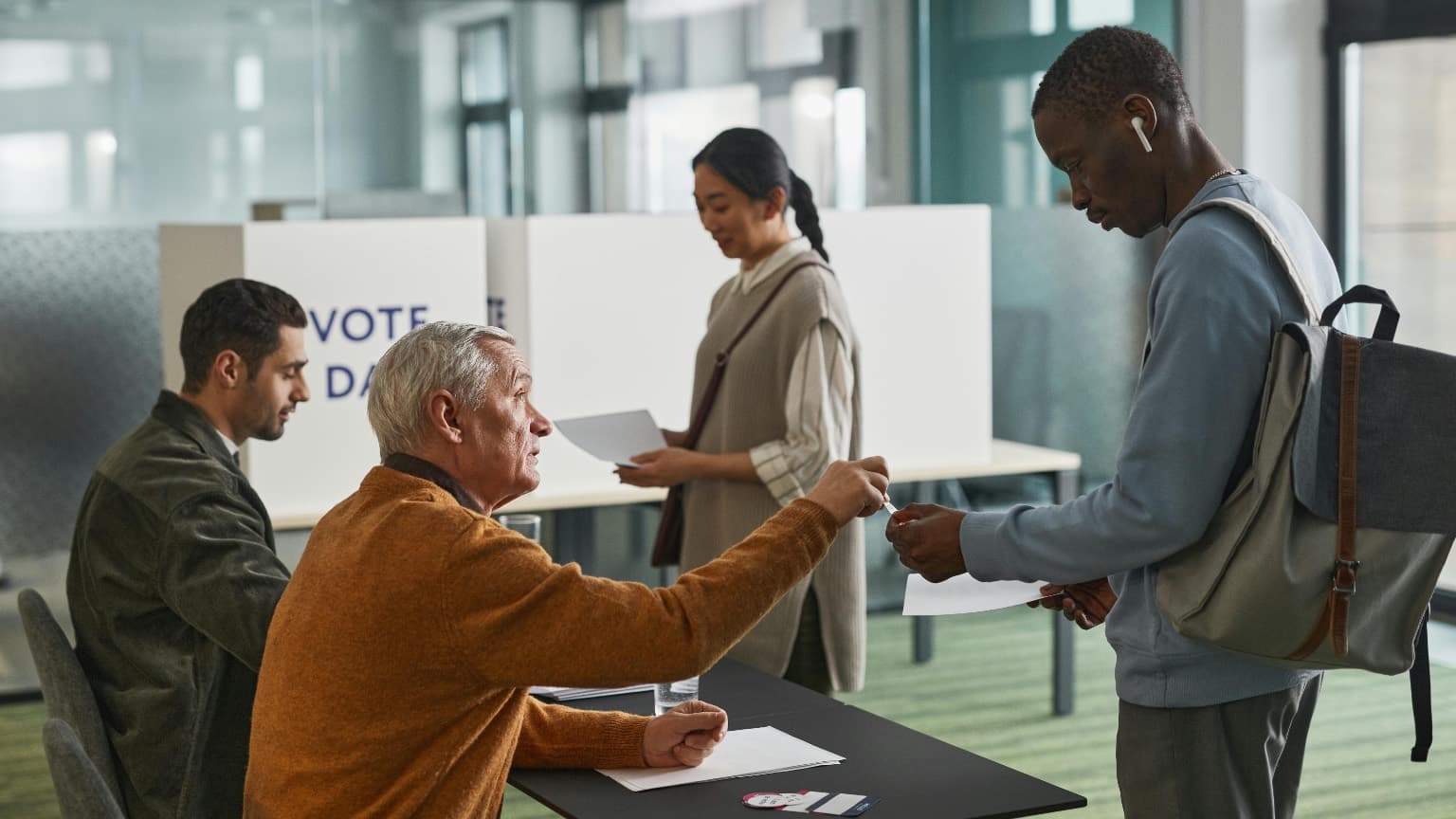 A poll worker takes a voter’s ID